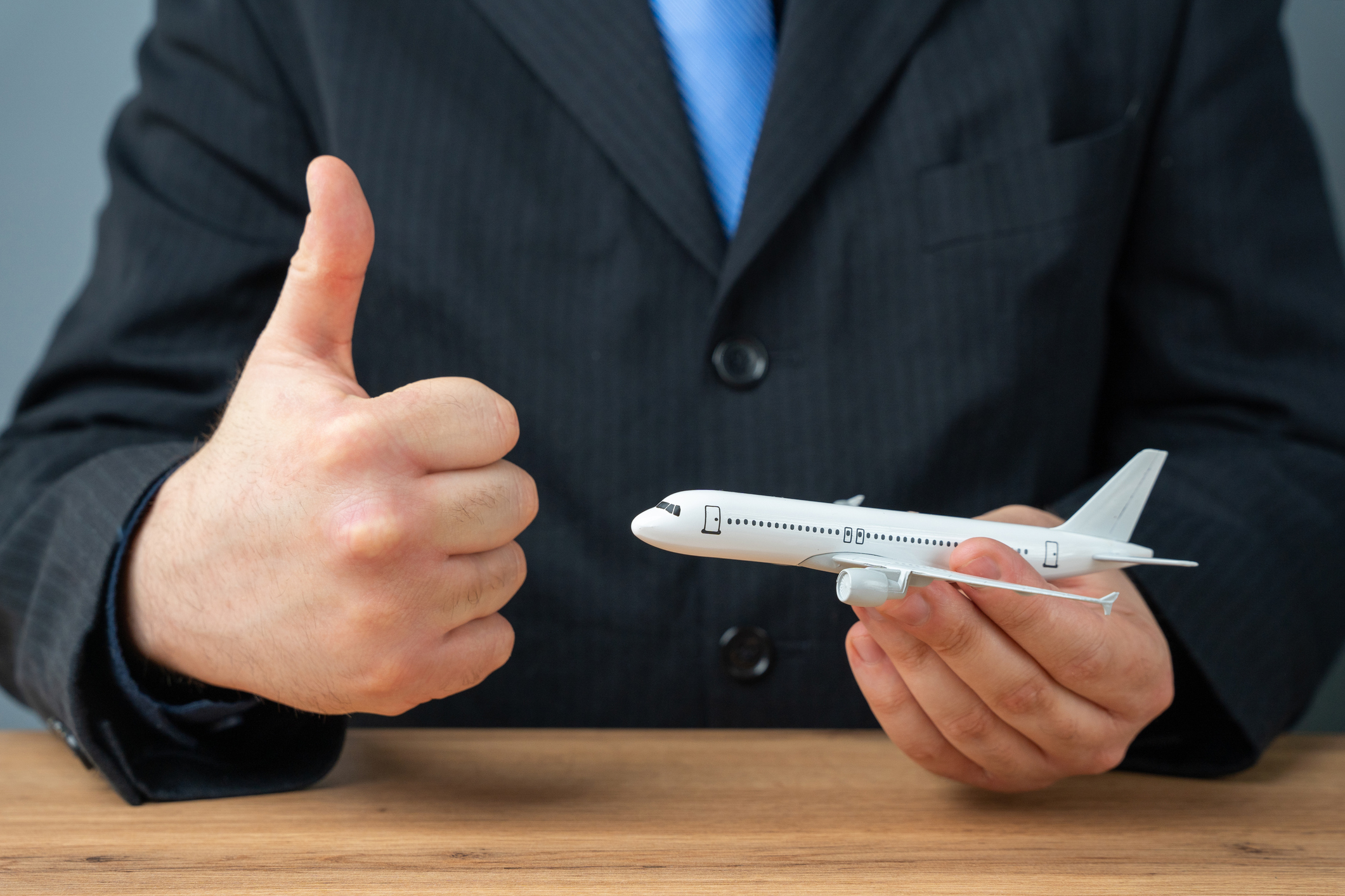 Businessman thumbs up holding airplane model.